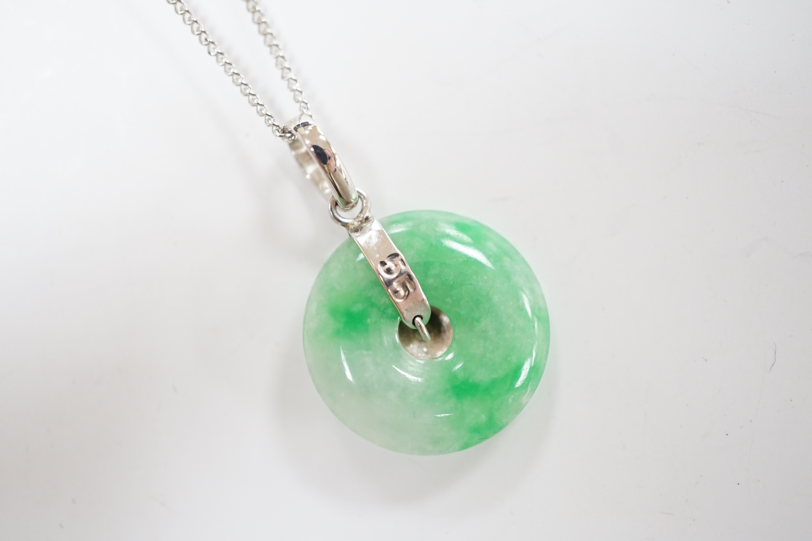 A modern 14k white metal and jade set disc pendant, 18mm, on a 9ct white gold chain, 42cm, gross weight 4.3 grams.